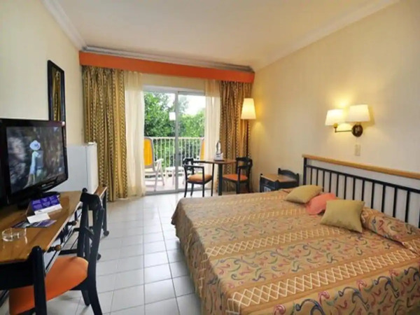 A double-bed, chairs, a table and a TV are in the Standard Room in Hotel Club Amigo Ancon