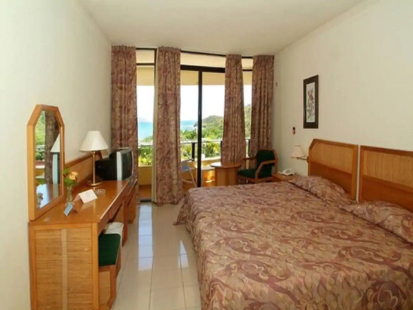 A double-bed, chairs and a dressing table in Tropical Room of Playa Ancon Hotel